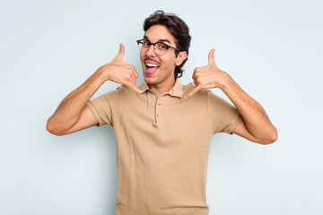 Young hispanic man isolated on blue background showing a mobile phone call gesture with fingers.