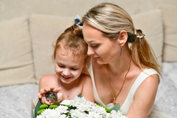 Mom and daughter with a bouquet of flowers and a hamster.