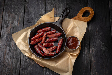 grilled sausages in a pan on a black background
