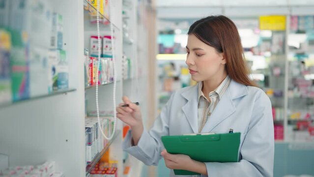 Professional woman pharmacist checking products in drugstore using noteboard.