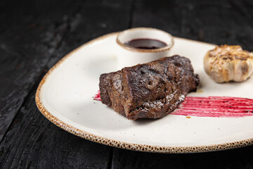 grilled meat with vegetables and spices on a black background
