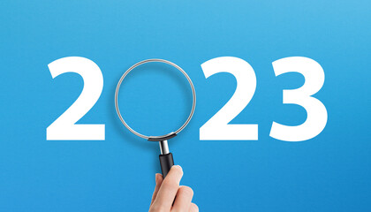 Happy New Year 2023 with magnifying glass on blue background
