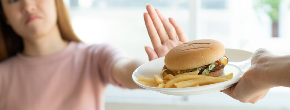 Woman on dieting for good health concept. Woman doing cross arms sign to refuse junk food or fast food (hamburger and potato fried) that have many fat.