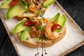 Bruschetta with seafood and greens on a white plate.

