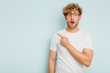 Young caucasian man isolated on blue background pointing to the side