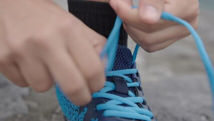 Closeup of hands tying shoelaces of sport shoe in slow motion.