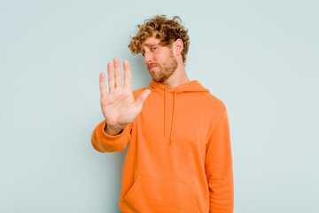 Young caucasian man isolated on blue background rejecting someone showing a gesture of disgust.