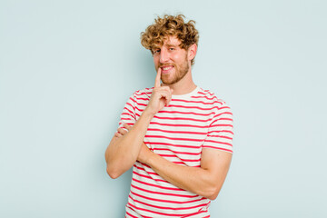 Young caucasian man isolated on blue background smiling happy and confident, touching chin with hand.