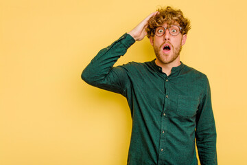 Young caucasian man isolated on yellow background shouts loud, keeps eyes opened and hands tense.