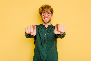 Young caucasian man isolated on yellow background cheerful smiles pointing to front.