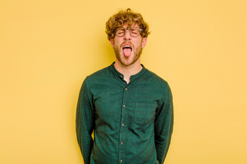 Young caucasian man isolated on yellow background funny and friendly sticking out tongue.