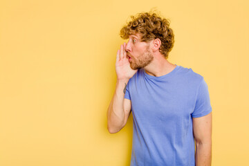 Young caucasian man isolated on yellow background is saying a secret hot braking news and looking...