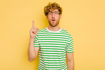 Young caucasian man isolated on yellow background pointing upside with opened mouth.