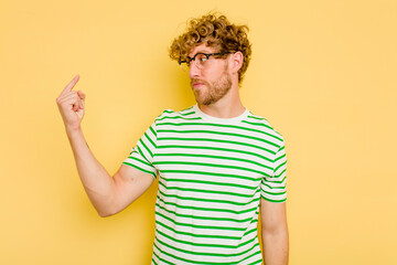 Young caucasian man isolated on yellow background pointing with finger at you as if inviting come closer.