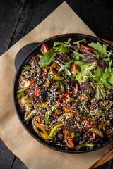 grilled meat with vegetables and spices on a black background
