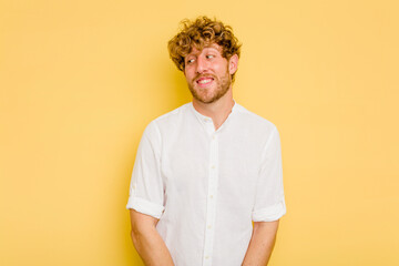 Young caucasian man isolated on yellow background laughs and closes eyes, feels relaxed and happy.