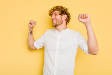 Young caucasian man isolated on yellow background celebrating a special day, jumps and raise arms with energy.