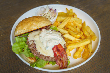 Bacon cheese hamburger and french fries on white dish