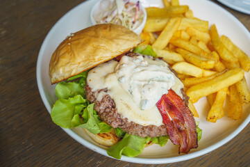 Bacon cheese hamburger and french fries on white dish