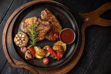 grilled meat with vegetables and spices on a black background
