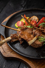 grilled meat with vegetables and spices on a black background
