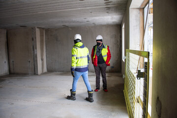 The architect of the building project and the construction manager walk around the interior of the new building