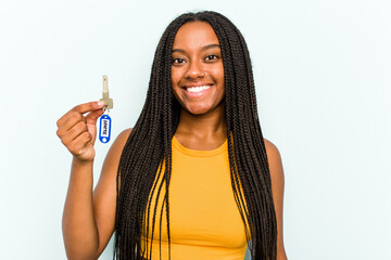 Young African American woman holding a home keys isolated on blue background happy, smiling and...