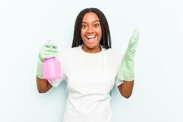 Young African American cleaner woman isolated on blue background receiving a pleasant surprise, excited and raising hands.