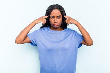 Fototapeta premium Young African American woman with braids hair isolated on blue background focused on a task, keeping forefingers pointing head.