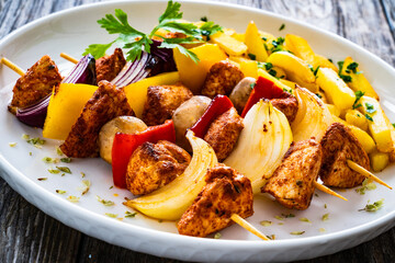 Chicken skewers - grilled meat with French fries on wooden background
