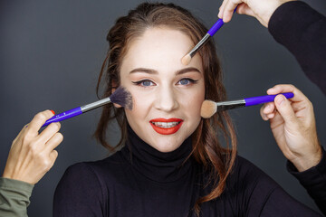 A girl with dark hair on a dark background with bright makeup