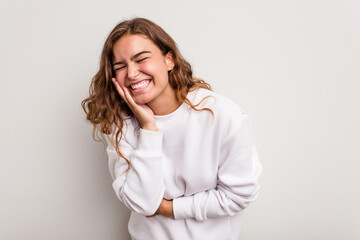 Young caucasian woman isolated on blue background laughs happily and has fun keeping hands on stomach.