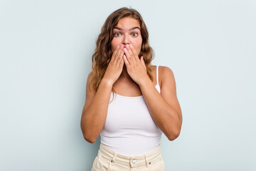 Young caucasian woman isolated on blue background shocked, covering mouth with hands, anxious to discover something new.