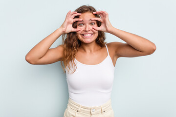 Young caucasian woman isolated on blue background keeping eyes opened to find a success opportunity.