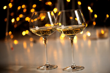 Two glasses of white wine or Champagne against shiny bokeh lights background