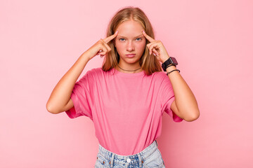 Caucasian teen girl isolated on pink background focused on a task, keeping forefingers pointing...