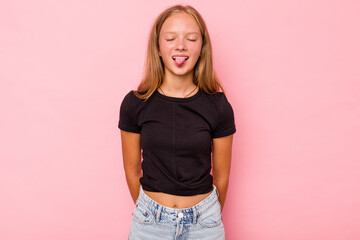 Caucasian teen girl isolated on pink background funny and friendly sticking out tongue.