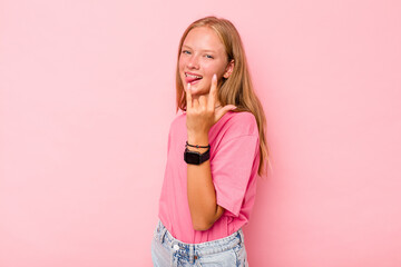 Caucasian teen girl isolated on pink background showing rock gesture with fingers