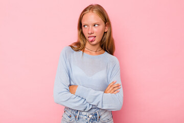 Fototapeta premium Caucasian teen girl isolated on pink background funny and friendly sticking out tongue.