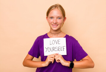 Little caucasian woman holding love yourself placard isolated on beige background