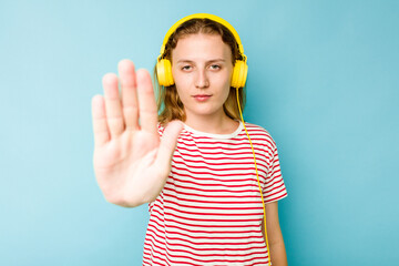 Young caucasian woman wearing headphones isolated on blue background standing with outstretched hand showing stop sign, preventing you.