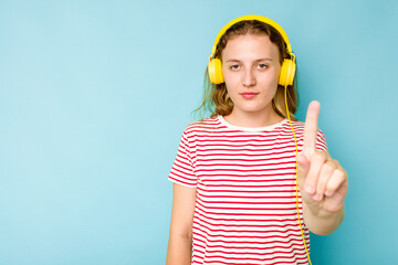 Young caucasian woman wearing headphones isolated on blue background showing number one with finger.