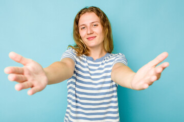 Young caucasian woman isolated on blue background showing a welcome expression.