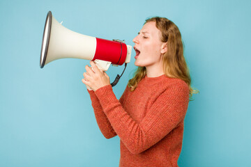 Young caucasian woman holding megaphone isolated on blue background