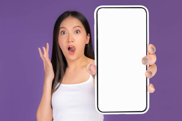 Obraz premium Beautiful Asian brunette woman cute girl in white tank top ,Excited surprised girl showing big smart phone with blank screen , white screen isolated purple background , Mock Up Image