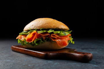 Salmon sandwich. A large roll. Dark mood.