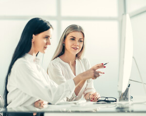 two employees are discussing something sitting at the office ta