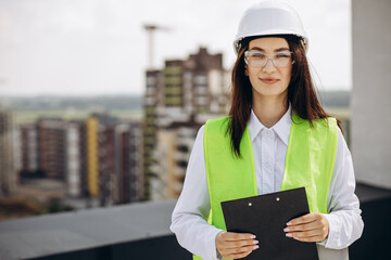 Business woman in white helmet standing on the roof of the building