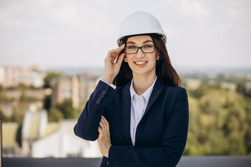 Business woman in white helmet standing on the roof of the building