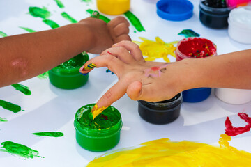 Children play with colorful paints on kids festival. Children's hands and finger soiled with dyes view. Children holiday and childhood concept.
